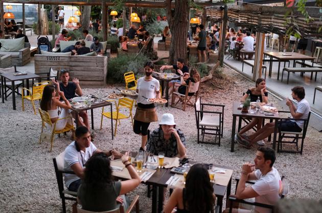 An employee carries pizzas for clients, who ordered them through the "Funky Pay" app, at Funky Pizza restaurant, where the app replaces waiters, in Palafrugell, near Girona, Costa Brava, Spain July 31, 2020. (REUTERS)