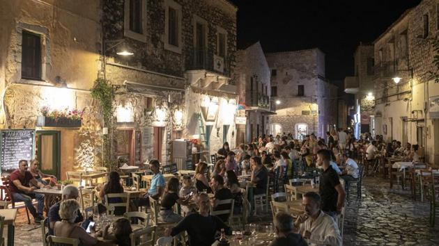 Tourists and local residents sit outside taverns in the town of Areopoli on the Mani Peninsula, Laconia, Peloponnese region, Greece on Wednesday July 29, 2020. Some travelers from Europe’s wealthier north appear more inclined to stay closer to home on concerns about coronavirus infections, which is a potential blow to countries like Spain, Italy and Greece, where tourism accounts for a big chunk of their economies. (Konstantinos Tsakalidis/Bloomberg)