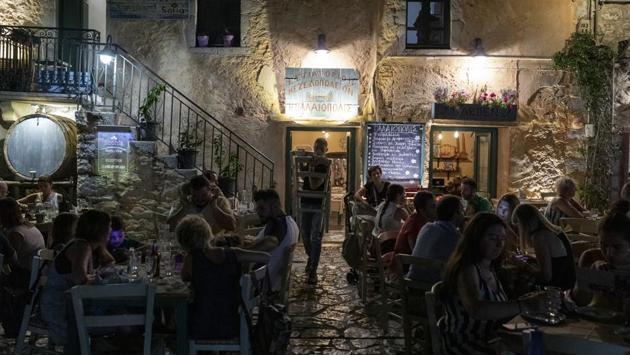 Tourists and local residents sit outside a tavern in the town of Areopoli on the Mani Peninsula, Laconia, Peloponnese region, Greece on Wednesday July 29, 2020. (Konstantinos Tsakalidis/Bloomberg) Tourists and local residents sit outside a tavern in the town of Areopoli on the Mani Peninsula, Laconia, Peloponnese region, Greece on Wednesday July 29, 2020. (Konstantinos Tsakalidis/Bloomberg)