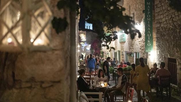 Tourists and local residents sit outside bars and taverns in the town of Areopoli on the Mani Peninsula, Laconia, Peloponnese region, Greece on July 29, 2020. (Konstantinos Tsakalidis/Bloomberg) Tourists and local residents sit outside bars and taverns in the town of Areopoli on the Mani Peninsula, Laconia, Peloponnese region, Greece on July 29, 2020. (Konstantinos Tsakalidis/Bloomberg)