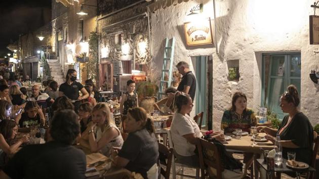 Tourists and local residents sit outside taverns in the town of Areopoli on the Mani Peninsula, Laconia, Peloponnese region, Greece on Wednesday July 29, 2020. (Konstantinos Tsakalidis/Bloomberg) Tourists and local residents sit outside taverns in the town of Areopoli on the Mani Peninsula, Laconia, Peloponnese region, Greece on Wednesday July 29, 2020. (Konstantinos Tsakalidis/Bloomberg)