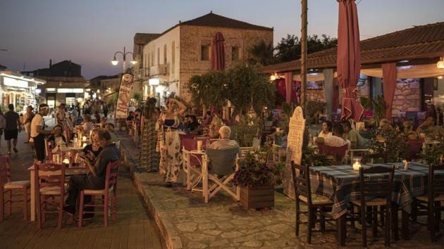 Tourists and local residents sit at a cafe bar in the main square of the town of Areopoli, Mani peninsula, Peloponnese region, Greece on Friday July 31, 2020. (Konstantinos Tsakalidis/Bloomberg) Tourists and local residents sit at a cafe bar in the main square of the town of Areopoli, Mani peninsula, Peloponnese region, Greece on Friday July 31, 2020. (Konstantinos Tsakalidis/Bloomberg)