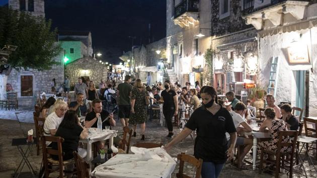 A waiter wears a face mask as she prepares a table in a tavern in the town of Areopoli on the Mani Peninsula, Laconia, Peloponnese region, Greece on Wednesday July 29, 2020. (Konstantinos Tsakalidis/Bloomberg) A waiter wears a face mask as she prepares a table in a tavern in the town of Areopoli on the Mani Peninsula, Laconia, Peloponnese region, Greece on Wednesday July 29, 2020. (Konstantinos Tsakalidis/Bloomberg)