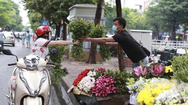 A seller hands flowers to a customer, both wearing face masks, in Hanoi on August 3. Vietnam, widely praised for its mitigation efforts since the coronavirus appeared in late January, is battling several new clusters of infection linked to the city of Danang after going more than three months without detecting any domestic transmission. (Hau Dinh / AP) A seller hands flowers to a customer, both wearing face masks, in Hanoi on August 3. Vietnam, widely praised for its mitigation efforts since the coronavirus appeared in late January, is battling several new clusters of infection linked to the city of Danang after going more than three months without detecting any domestic transmission. (Hau Dinh / AP)