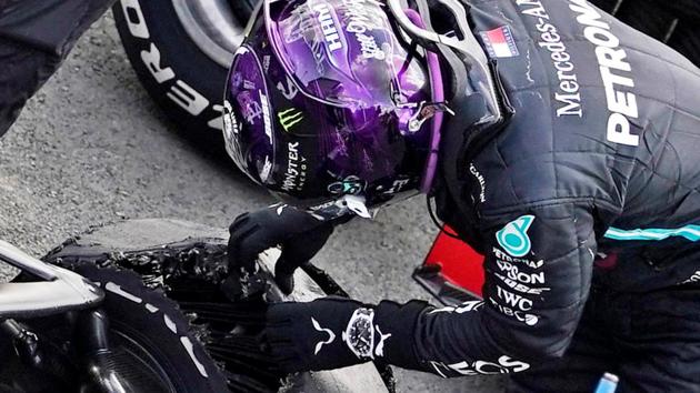 Mercedes' Lewis Hamilton looks at his tyre after winning the race with a puncture on the final lap.(Pool via REUTERS)