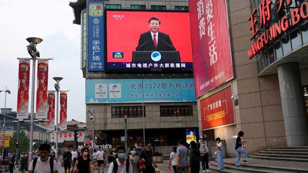 People wearing face masks following the coronavirus disease (Covid-19) outbreak, walk past a giant screen broadcasting a news footage of Chinese President Xi Jinping at a shopping area in Beijing, China July 31, 2020. (REUTERS)