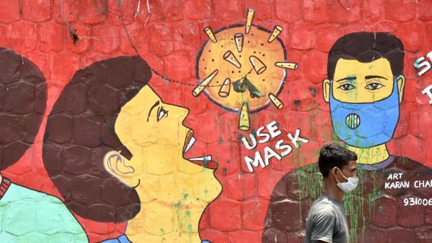 A man wearing a face mask walks past a COVID-19 awareness mural in Jamia Nagar, New Delhi on August 4. Day before yesterday on August 4, Delhi had 9,897 active cases of the disease. This was the first time since May 29, that active cases in Delhi dropped below 10,000. Active cases in Delhi had touched an all time high of 28,329 on June 27. (Vipin Kumar / HT Photo)