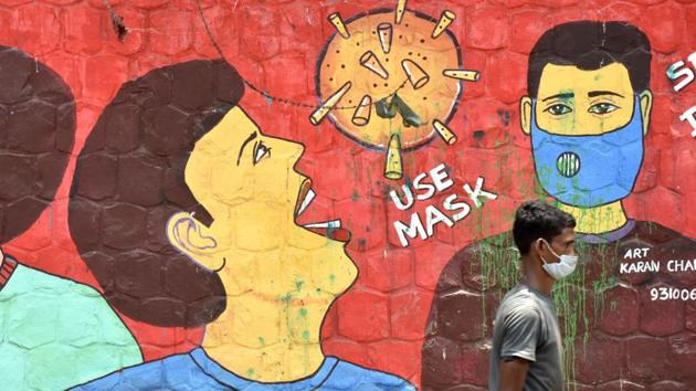 A man wearing a face mask crosses a mural on the use of face masks as protection against the coronavirus, at Jamia Nagar in New Delhi on August 4. India’s tally of the coronavirus disease (Covid-19) has risen to more than 1.9 million after a seventh consecutive day of over 50,000 being recorded in the last 24 hours, Union health ministry data showed on August 5. (Vipin Kumar / HT Photo)