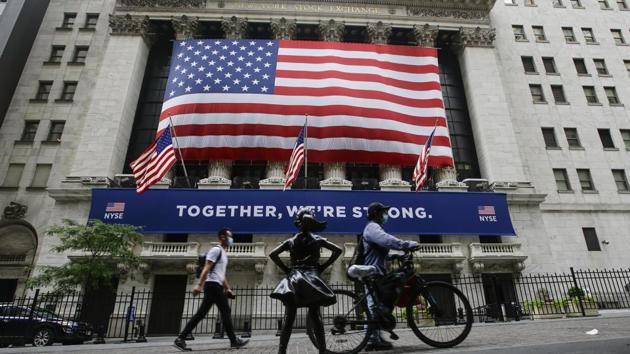 Pedestrians wearing protective masks during the coronavirus pandemic pass by the New York Stock Exchange in New York. (AP) Pedestrians wearing protective masks during the coronavirus pandemic pass by the New York Stock Exchange in New York. (AP)
