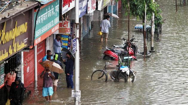 People walk through a waterlogged road during rains, in Mumbai.(ANI)