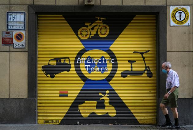 A man wearing a protective face mask walks past a closed rent shop of electric vehicles, after Catalonia's regional authorities announced restrictions to contain the spread of the coronavirus disease (COVID-19) in Barcelona, Spain August 4, 2020. (REUTERS)