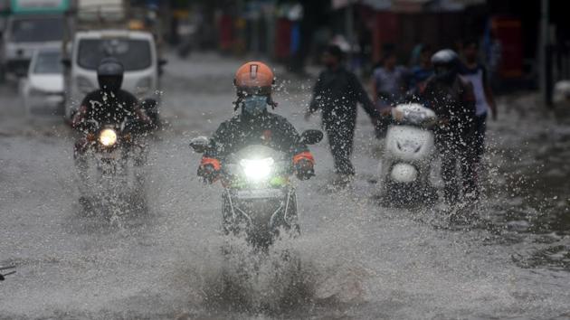 Commuters wade through a water logged road at LBS road in Kurla, Mumbai on August 5. According to the PTI report, many motorists abandoned their vehicles in flooded streets after they broke down, which severely affected traffic movement. (Satish Bate / HT Photo)