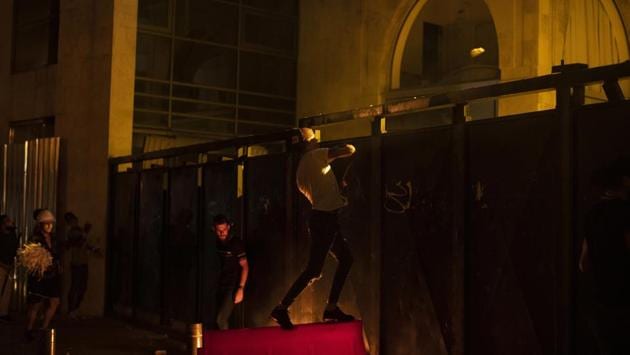 Demonstrators are seen throwing stones at the riot police while standing behind an iron gate in Beirut on August 6. Lebanon recorded 255 coronavirus cases on August 6, its highest single day infection tally, after the blast turned the planned lockdown upside down and sent thousands streaming into overflowing hospitals. (Hassan Ammar / AP)