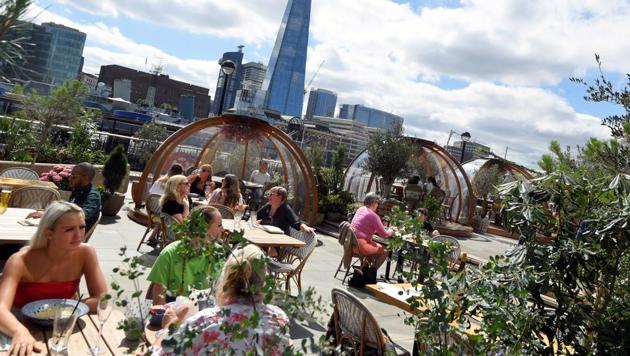 People eat outside and inside private dining pods, on the terrace of a restaurant, in London, Britain, August 6, 2020.(REUTERS)