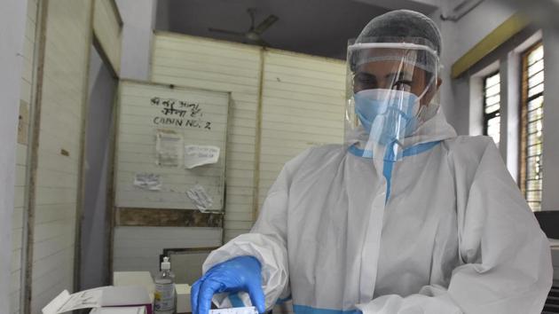 A health worker in PPE kit shows a coronavirus testing slide.(Sonu Mehta/HT PHOTO) A health worker in PPE kit shows a coronavirus testing slide.(Sonu Mehta/HT PHOTO)