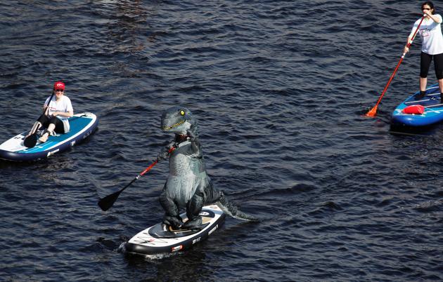 A participant in a dinosaur costume makes their way on the Fontanka river during the Fontanka-SUP stand up paddle boarding festival in Saint Petersburg, Russia August 8, 2020. (REUTERS)