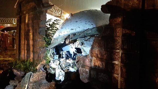 A part of the Air India Express flight is seen through a broken wall after it skidded off a runway while landing at the airport in Kozhikode, Kerala on Friday.(AP Photo)