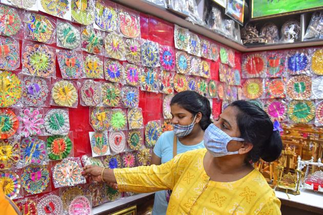 A woman buys dresses for Lord Krishna from a shop ahead of the Janmashtami festival, in Bikaner, Saturday, Aug 8, 2020. (PTI)