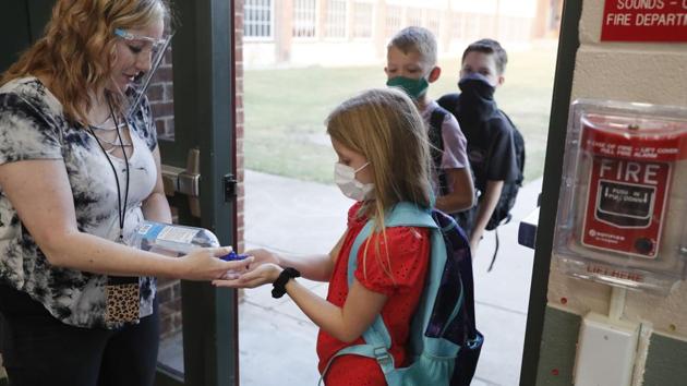 Wearing masks to prevent the spread of Covid-19, elementary school students use hand sanitizer before entering school for classes in Godley, Texas. As schools reopen around the country, their ability to quickly identify and contain coronavirus outbreaks before they get out of hand is about to be put to the test. (AP) Wearing masks to prevent the spread of Covid-19, elementary school students use hand sanitizer before entering school for classes in Godley, Texas. As schools reopen around the country, their ability to quickly identify and contain coronavirus outbreaks before they get out of hand is about to be put to the test. (AP)