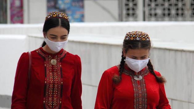 Women wearing protective face masks, used as a preventive measure against the spread of the coronavirus disease (Covid-19), walk along the street in Ashgabat, Turkmenistan.(REUTERS)