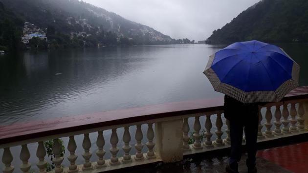 A local person walking past Naini Lake in Nainital district on Sunday amid heavy rain.(RAAJIV KALA/HT PHOTO.)