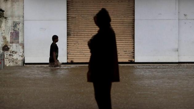 A man wades through a water logged street in Mumbai on August 5. Maharashtra breached the 500,000 case mark 10 days after its tally crossed 400,000 on July 29. The 100,000 cases before that grim milestone were reported in 11 days. (Rajanish Kakade / AP)