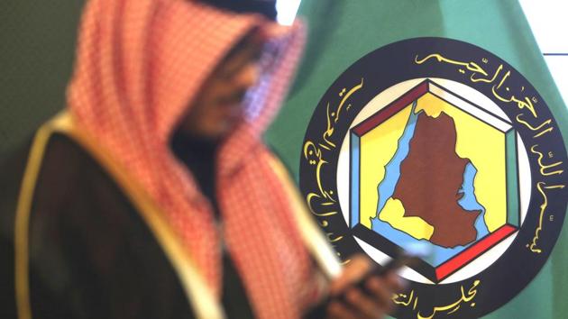 A man looks at his mobile phone in front of the flag of the Gulf Cooperation Council, GCC, in Kuwait City.(AP)