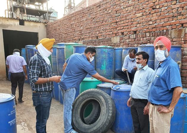 Excise officials check drums containing illicit chemicals at a unit in Dera Bassi in Mohali on Sunday.(HT Photo)