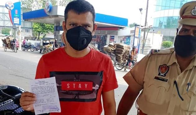 A person shows his challan while wearing a mask given by the police after fining him not having one on in Ludhiana on Sunday. (HT Photo) A person shows his challan while wearing a mask given by the police after fining him not having one on in Ludhiana on Sunday. (HT Photo)
