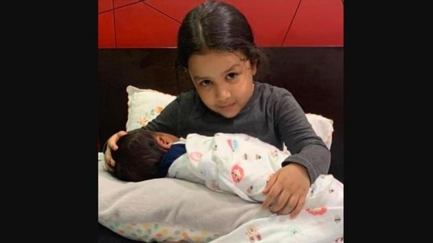A picture of Ziva Dhoni sitting on a bed with a baby in her lap shared by Sakshi Dhoni.(Instagram/@sakshisingh_r)