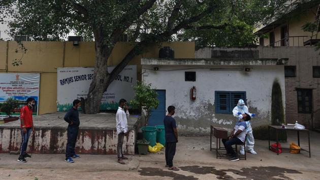 People wait their turn while a health worker collects a nasal swab sample for coronavirus testing at Ramjas School in New Delhi on August 7. According to the ICMR, India performed 719,364 Covid-19 tests on August 8 alone, taking the total number of daily testing closer to the ICMR target of one million per day by the end of August. (Biplov Bhuyan / HT Photo)
