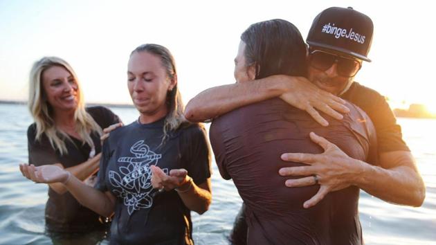 Two worshippers (C) are comforted after being baptized in the Pacific Ocean at the Saturate OC beach revival held on August 7 at Newport Beach in defiance of a ban on mass gatherings. In the US, new cases are running at about 54,000 a day — an immensely high number even when taking into account the country’s large population. While that’s down from a peak of over 70,000 last month, cases are rising in nearly 20 states. (MArio tama / Getty Images / AFP)