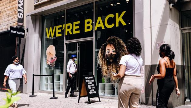 Pedestrians wearing protective masks pass in front of a Steve Madden Ltd. store advertising its reopening in New York on August 6. Health officials believe the actual number of infections is perhaps 10 times higher, or closer to 50 million, given testing limitations and the fact that as many as 40% of all those who are infected have no symptoms, the AP reported. (Nina Westervelt / Bloomberg)