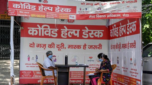 A medical staff (L) working at a registration desk for COVID-19 coronavirus tests at Pyare Lal Sharma district hospital in Meerut. The ICMR is now trying to include Reverse Transcription-Polymerase Chain Reaction (RT-PCR) machines in Covid-19 testing at government labs since RT-PCR is the most preferred process in testing for the virus. (Prakash Singh / AFP)