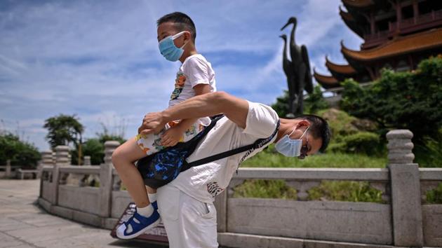 A man plays with his nephew, both wearing face masks, while visiting the Yellow Crane Tower in Wuhan on August 7. (Hector Retamal / AFP)