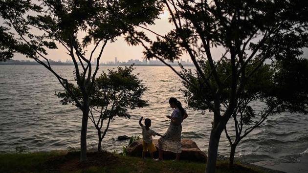 A woman plays with her son by East Lake in Wuhan on August 5. Wuhan has also had time to look back on its trauma, though only some memories make it into the official narrative. (Hector Retamal / AFP)