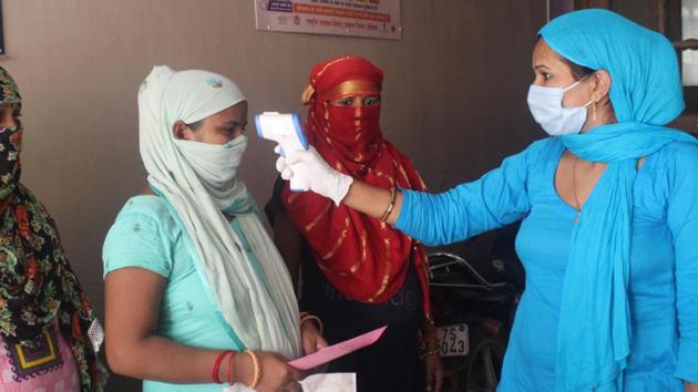 A health worker uses an infrared thermometer to screen a woman during swab sample collection for Covid-19 testing in Gurugram on Monday. India’s Covid-19 tally has now surged to more than 2.26 million, data showed on Tuesday. (HT Photo/Rahul Grover)