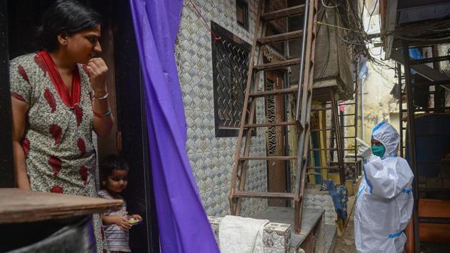 A health worker wearing Personal Protective Equipments (PPE) urges a resident to get her temperature and oxygen level checked during a COVID-19 coronavirus screening in Mumbai on August 11. CM Thackeray has also sought the support of the Central government to set up an infectious disease hospital and research facility near Mumbai. (Indranil Mukherjee / AFP)
