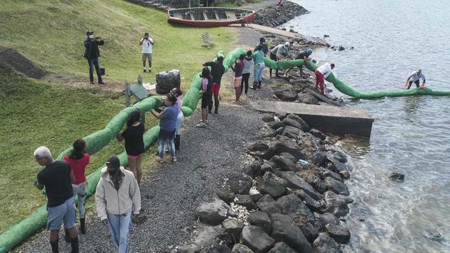 Volunteers carry a handmade oil barrier to block leaked oil from the ship at the beach in Bambous Virieux in Mauritius on August 10. AFP reported that thousands of volunteers have turned out along the coast since August 7, stringing together miles of improvised floating barriers made of straw in a desperate attempt to hold back the oily tide. (L'Express Maurice / AFP)