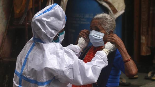 A health worker helps a woman wear a mask before screening her for COVID-19 in Mumbai on August 11. Gujarat and Maharashtra have the worst case fatality rate (CFR) in the country at 3.74% and 3.44%, respectively. Maharashtra’s death toll from the viral outbreak stands at 18,306 . (Rafiq Maqbool / AP)