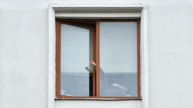 A person wearing a white bracelet - a symbol of the opposition - gestures from inside a window as women protest against police violence in Minsk on August 12. The anti-government demonstrators still turned out for a third straight day to protest the vote results, despite Tsikhanouskaya backed out of the elections and left for Lithuania. (Sergei Gapon / AFP)