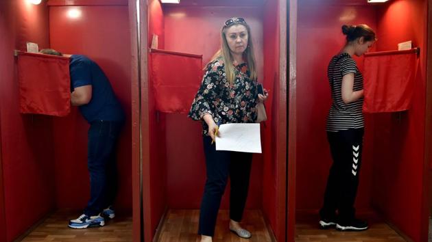 A woman walks out of a voting booth after casting her ballot during the presidential election in Minsk on August 9. Belarus went to vote for the Presidential elections on August 9. (Sergei Gapon / AFP)