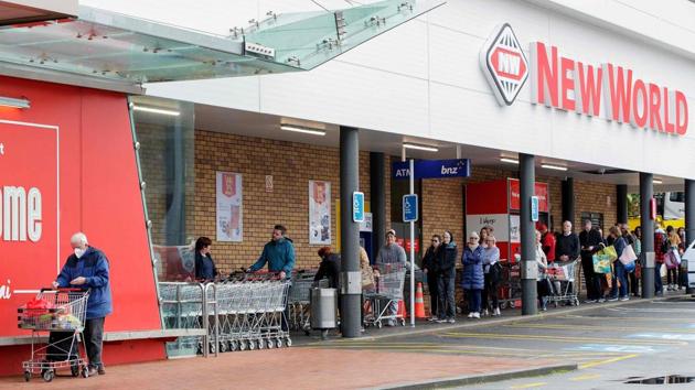 Shoppers queue outside a supermarket in the suburb of Devonport in Auckland on August 12. AFP reported that as the news of the new cases spread, panic buying returned to supermarkets and people stood in long queues at COVID-19 testing stations. (David Rowland / AFP) 