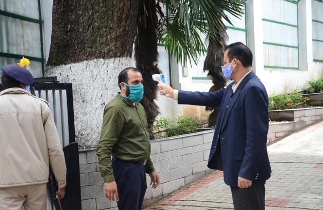 A security personnel running a thermal scan check on a visitor at Himachal chief minister Jai Ram Thakur’s residence, Oak Over, in Shimla on Thursday.(Deepak Sansta/HT)