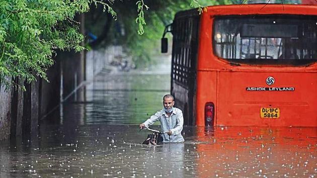 A cyclist makes his way while a bus is seen partially submerged at Zakhira underpass.