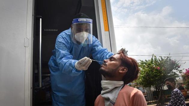 A health worker in PPE coveralls collects a swab sample from a person for coronavirus rapid antigen test, at Keshopur in New Delhi, on Wednesday.(Sanchit Khanna/HT Photo)