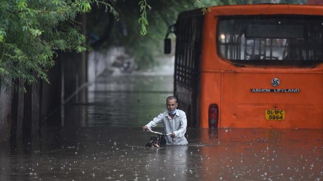 A cyclist makes his way out against the backdrop of a partially submerged bus at Zakhira underpass due to heavy rains and waterlogging in New Delhi on August 13. According to PTI, pictures and videos of vehicles and people wading through waist-deep water were widely shared on social media platforms. (Sanchit Khanna / HT Photo) 