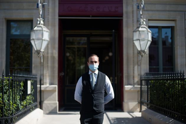 A doorman wearing a protective face mask stands outside the La Reserve hotel, one of the 12 high-end hotels in Paris that are classified as palaces, in this arranged photograph in Paris, France, on Wednesday, Aug. 12, 2020. (Bloomberg)
