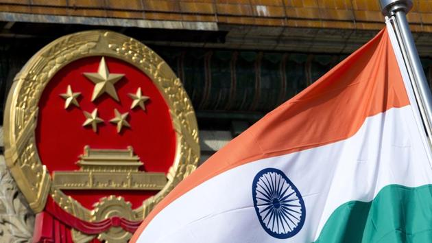 An Indian national flag is flown next to the Chinese national emblem outside the Great Hall of the People in Beijing.(AP)