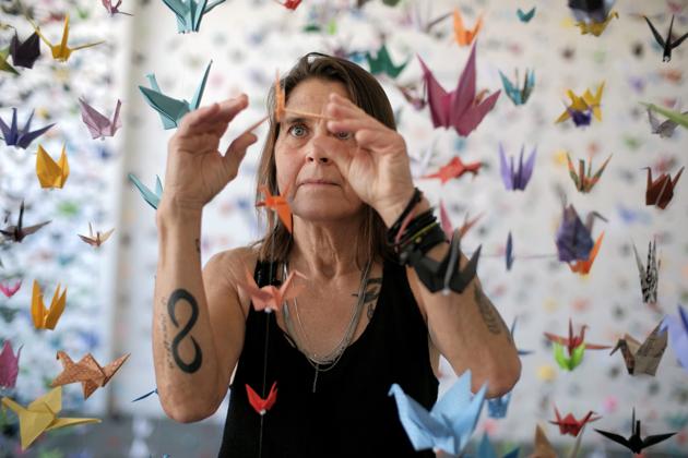 Artist Karla Funderburk, owner of Matter Studio Gallery, adjusts one of of the thousands of origami cranes hanging during an exhibit honoring the victims of COVID-19, Tuesday, Aug. 11, 2020, in Los Angeles. Funderburk started making the cranes three months earlier, stringing the paper swans in pink, blue, yellow and many other colors together and hanging them in her gallery. (AP Photo/Richard Vogel) (AP)